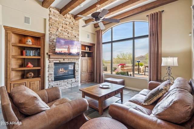 living area with a high ceiling, beam ceiling, a fireplace, ceiling fan, and built in shelves