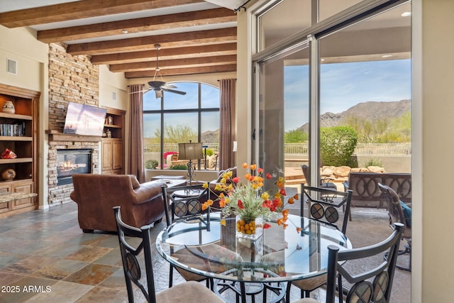 dining room with a mountain view, stone finish floor, built in features, beamed ceiling, and a fireplace