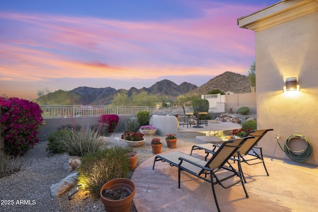 patio terrace at dusk with a fenced backyard and a mountain view