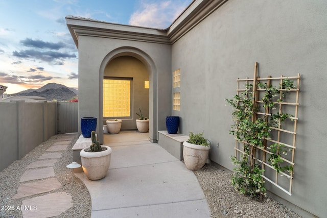 view of exterior entry with fence, a patio, and stucco siding