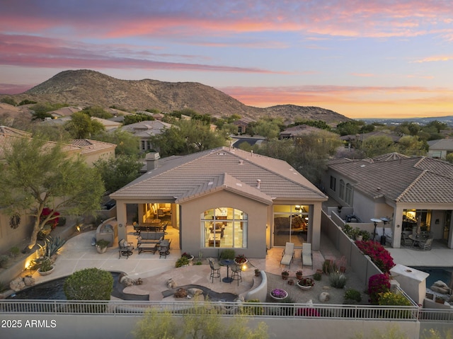 rear view of property with a mountain view, a patio, stucco siding, a tile roof, and a fenced backyard