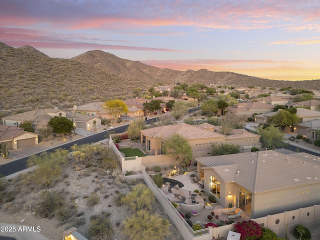 aerial view at dusk featuring a mountain view and a residential view