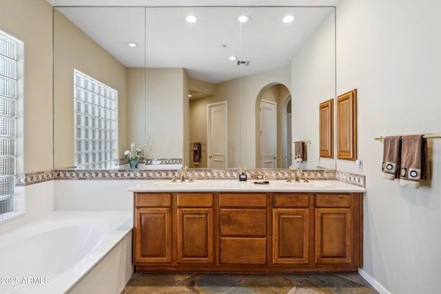 full bathroom with a bath, recessed lighting, double vanity, and a sink