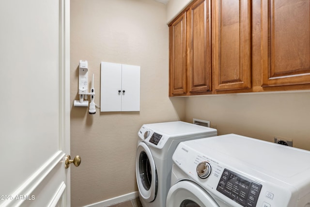 washroom featuring washing machine and clothes dryer, cabinet space, and baseboards