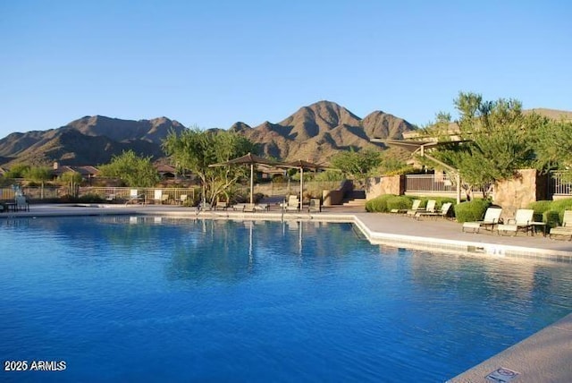 pool featuring a mountain view, a patio, and fence