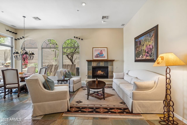 living room featuring visible vents, a fireplace, baseboards, and stone tile flooring