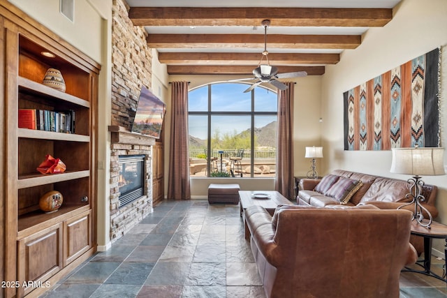 living room with beam ceiling, stone tile flooring, visible vents, ceiling fan, and a stone fireplace