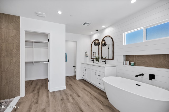 11509 W Langford Ct, Youngtown, AZ 85363 - bathroom featuring vanity, wood finished floors, a soaking tub, recessed lighting, and a walk in closet