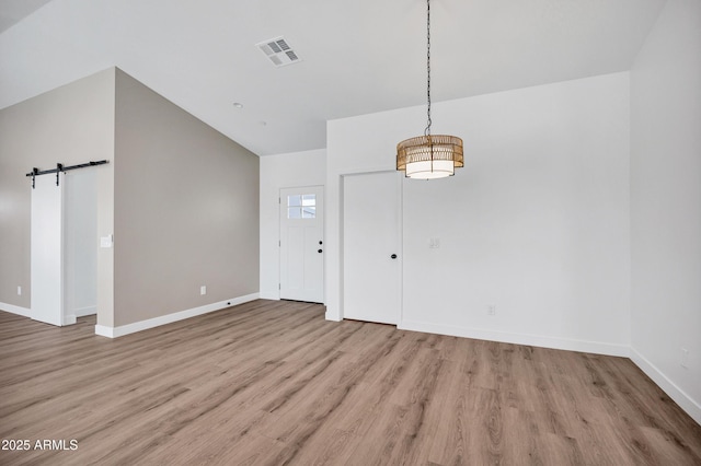 11509 W Langford Ct, Youngtown, AZ 85363 - unfurnished dining area with a barn door, light wood-style flooring, baseboards, vaulted ceiling, and a chandelier