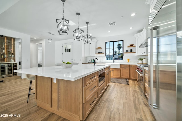 kitchen with sink, hanging light fixtures, a spacious island, high end appliances, and a kitchen bar