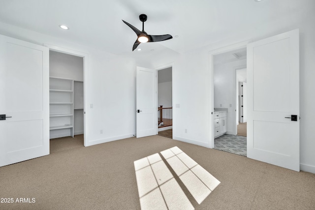 unfurnished bedroom with ceiling fan, a walk in closet, and light carpet