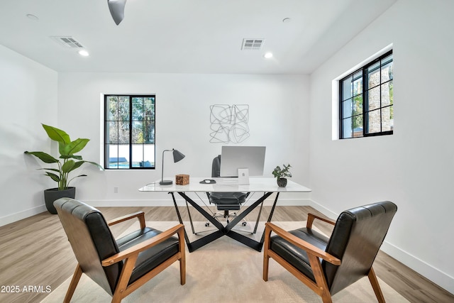 home office with a healthy amount of sunlight and light hardwood / wood-style floors