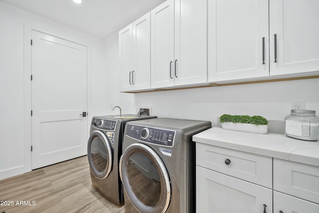 washroom with washer and dryer, light hardwood / wood-style floors, and cabinets