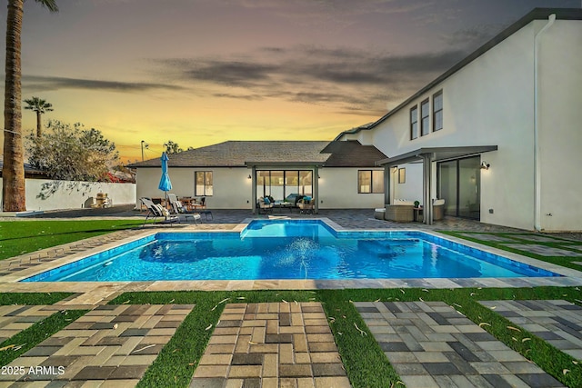 pool at dusk featuring a patio area