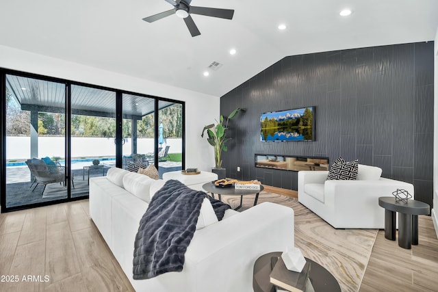 living room featuring ceiling fan, light hardwood / wood-style floors, and vaulted ceiling