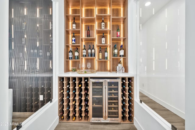 wine cellar featuring indoor bar, hardwood / wood-style floors, and wine cooler