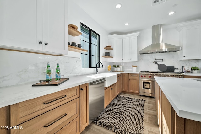 kitchen with appliances with stainless steel finishes, sink, white cabinets, and wall chimney exhaust hood