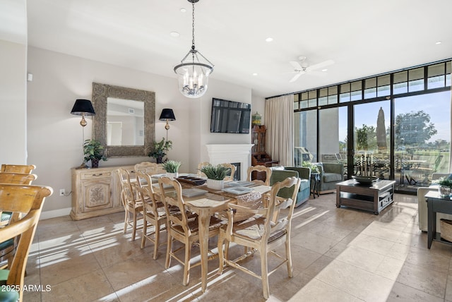 tiled dining area with ceiling fan with notable chandelier and expansive windows