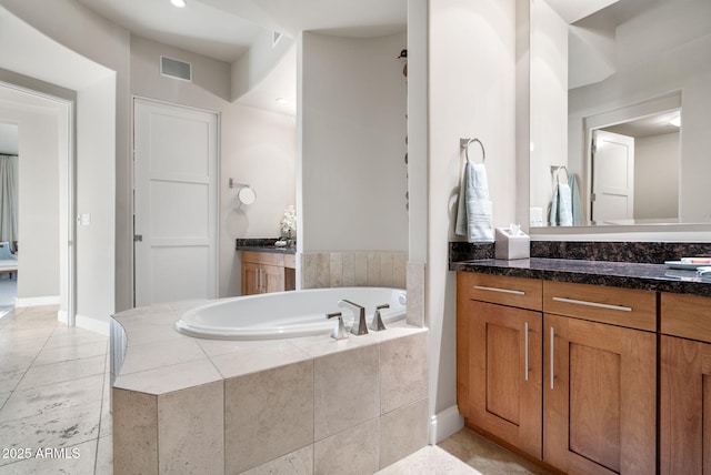 bathroom with a relaxing tiled tub and vanity