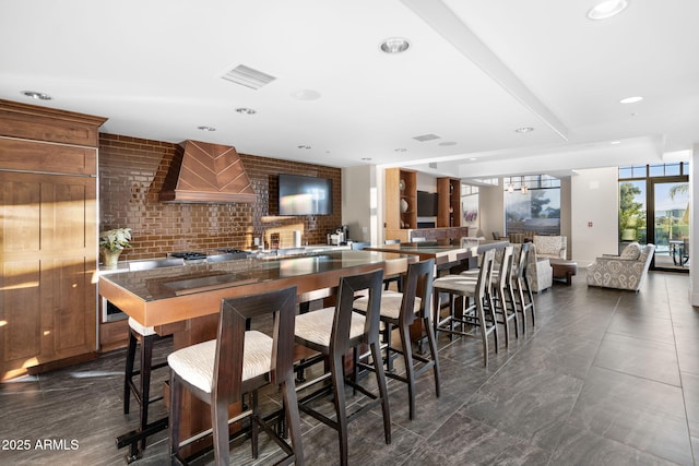 kitchen featuring a wall of windows, kitchen peninsula, a breakfast bar area, and custom exhaust hood