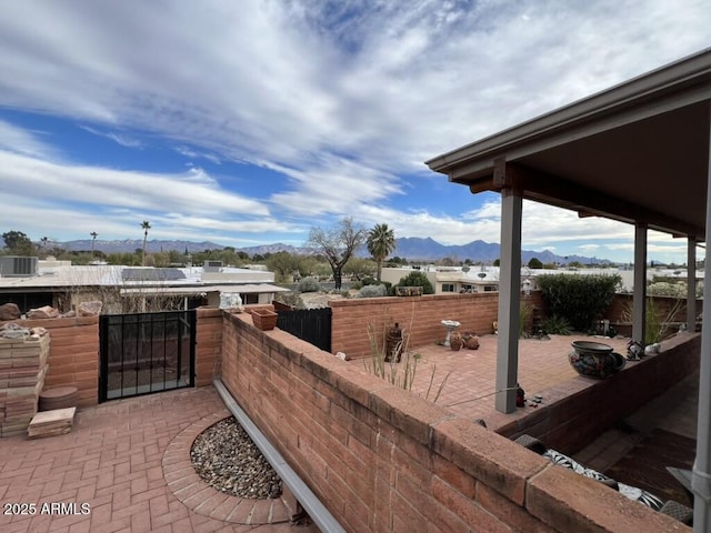 view of patio / terrace featuring central AC, a mountain view, and fence