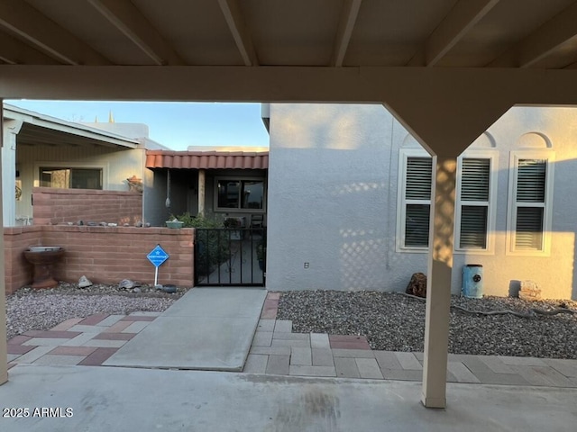 doorway to property featuring a gate, fence, and stucco siding