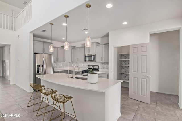 kitchen with a kitchen island with sink, stainless steel appliances, decorative light fixtures, and a kitchen breakfast bar