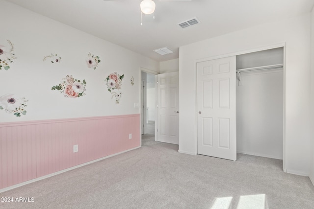 unfurnished bedroom with ceiling fan, light colored carpet, and a closet