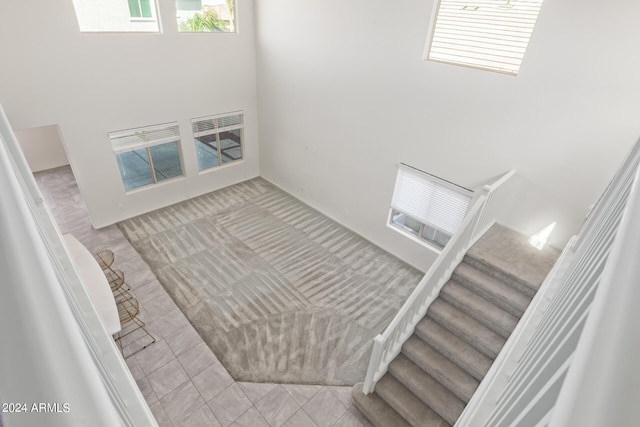 stairs with light tile flooring and a towering ceiling