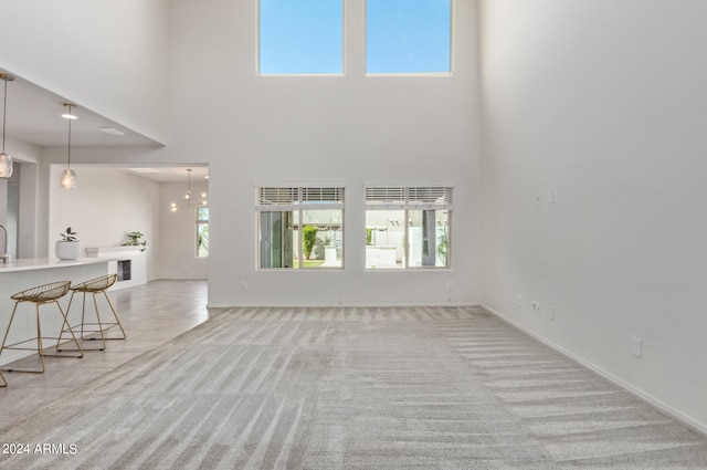 unfurnished living room featuring light tile flooring and a towering ceiling