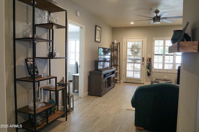 doorway featuring a ceiling fan, baseboards, light wood-style flooring, and recessed lighting