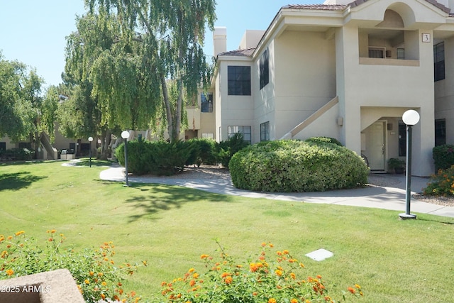 view of property exterior with a chimney, a tile roof, stucco siding, and a yard