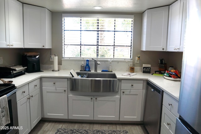 kitchen featuring stainless steel appliances, a sink, light countertops, and white cabinetry