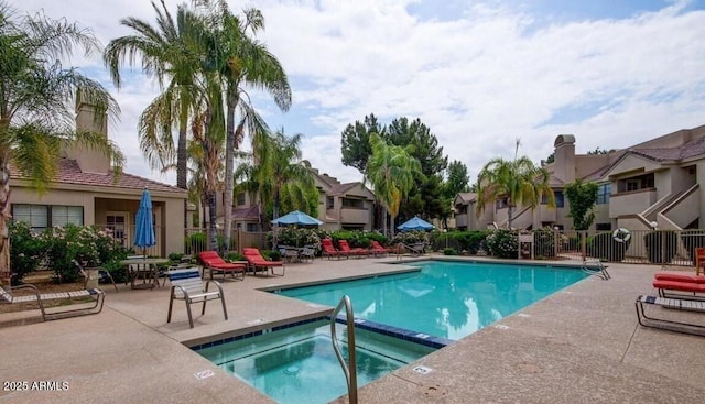 community pool featuring a community hot tub, a patio, a residential view, and fence