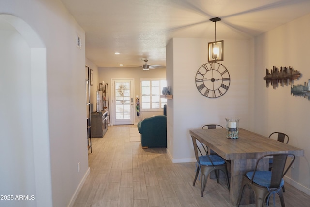 dining space featuring baseboards, light wood-style flooring, arched walkways, a ceiling fan, and recessed lighting