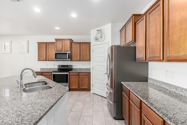 kitchen featuring light stone countertops, sink, light tile patterned floors, and stainless steel appliances