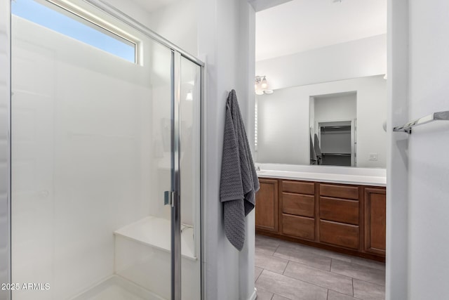 bathroom featuring a shower with door and vanity