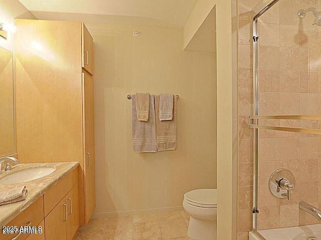 bathroom featuring a shower with shower door, toilet, vanity, tile patterned floors, and baseboards