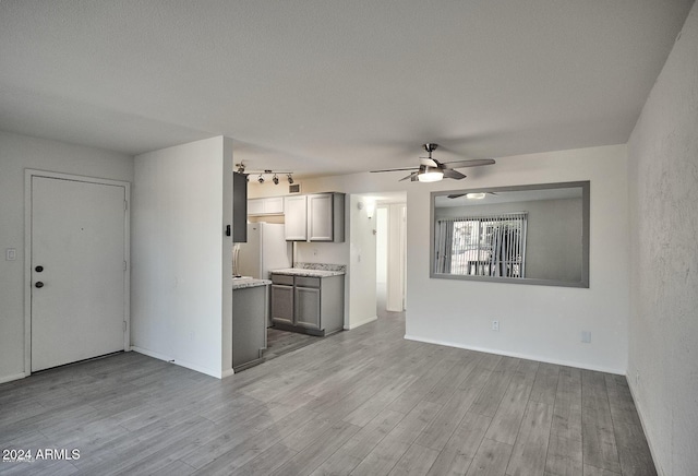 unfurnished living room with ceiling fan, a textured ceiling, and light wood-type flooring