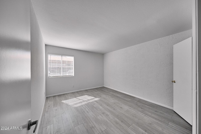 spare room featuring a textured ceiling and light wood-type flooring