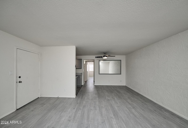 unfurnished living room featuring ceiling fan, light hardwood / wood-style floors, and a textured ceiling