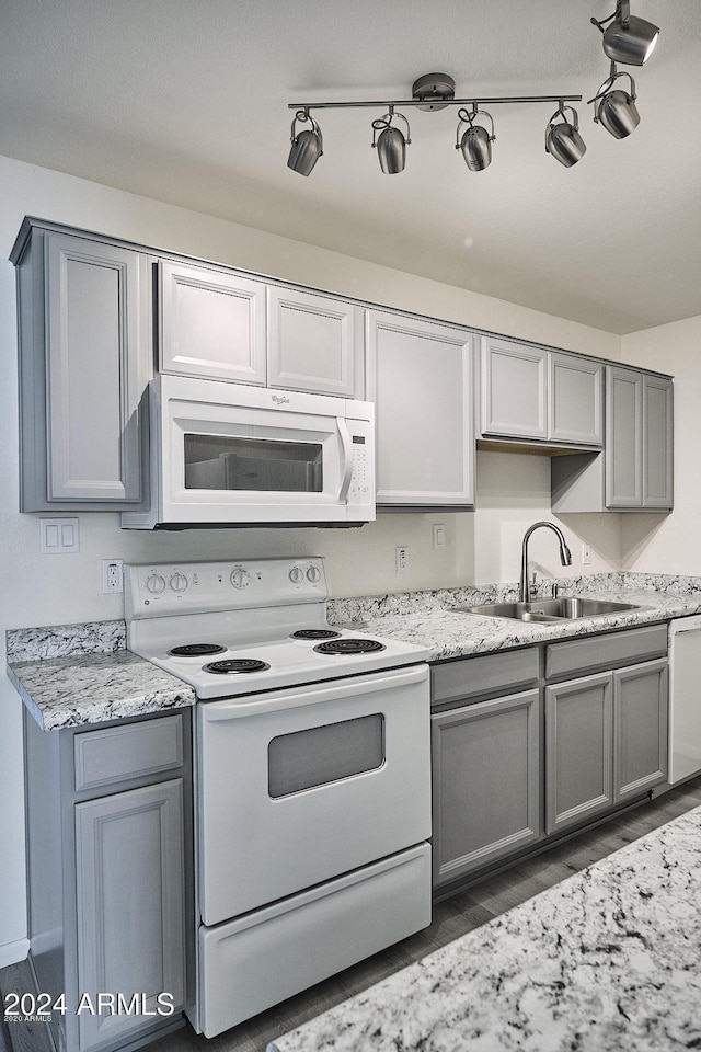 kitchen with gray cabinets, light stone counters, sink, and white appliances