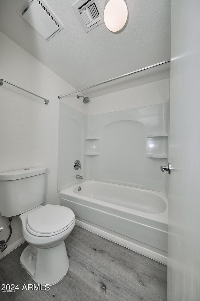 bathroom featuring hardwood / wood-style flooring, toilet, and washtub / shower combination