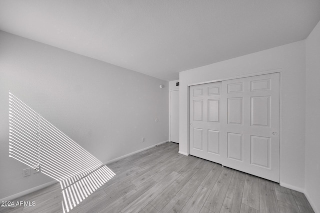 unfurnished bedroom featuring light hardwood / wood-style floors and a closet