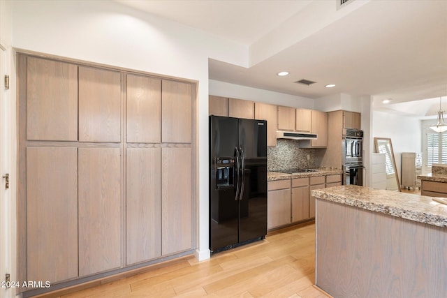 kitchen featuring light brown cabinets, black appliances, light stone countertops, light wood-type flooring, and tasteful backsplash