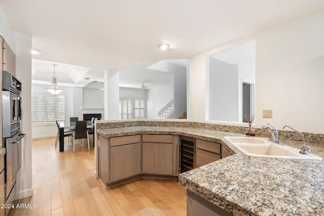 kitchen featuring light brown cabinets, sink, ceiling fan, light hardwood / wood-style floors, and kitchen peninsula