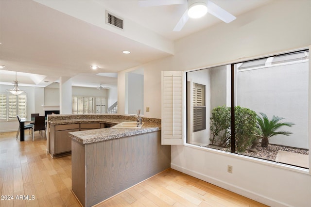 kitchen with ceiling fan, sink, hanging light fixtures, light hardwood / wood-style flooring, and kitchen peninsula