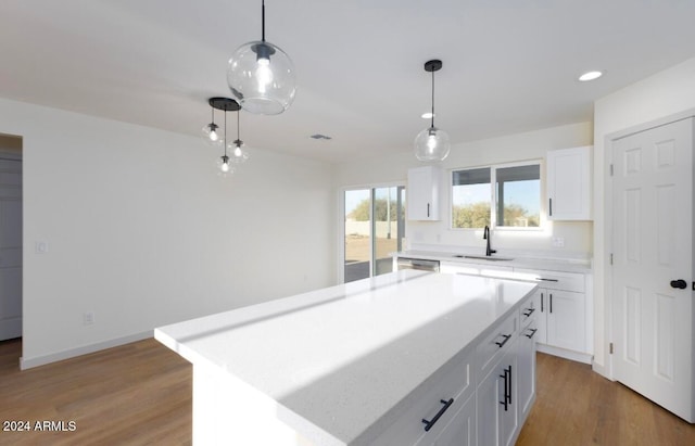 kitchen featuring decorative light fixtures, a center island, white cabinetry, and sink