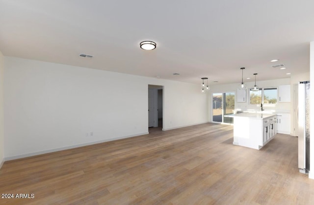 interior space with stainless steel fridge, pendant lighting, a center island, light hardwood / wood-style floors, and white cabinetry