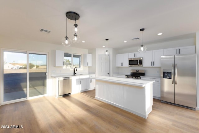 kitchen with pendant lighting, white cabinets, sink, light wood-type flooring, and stainless steel appliances